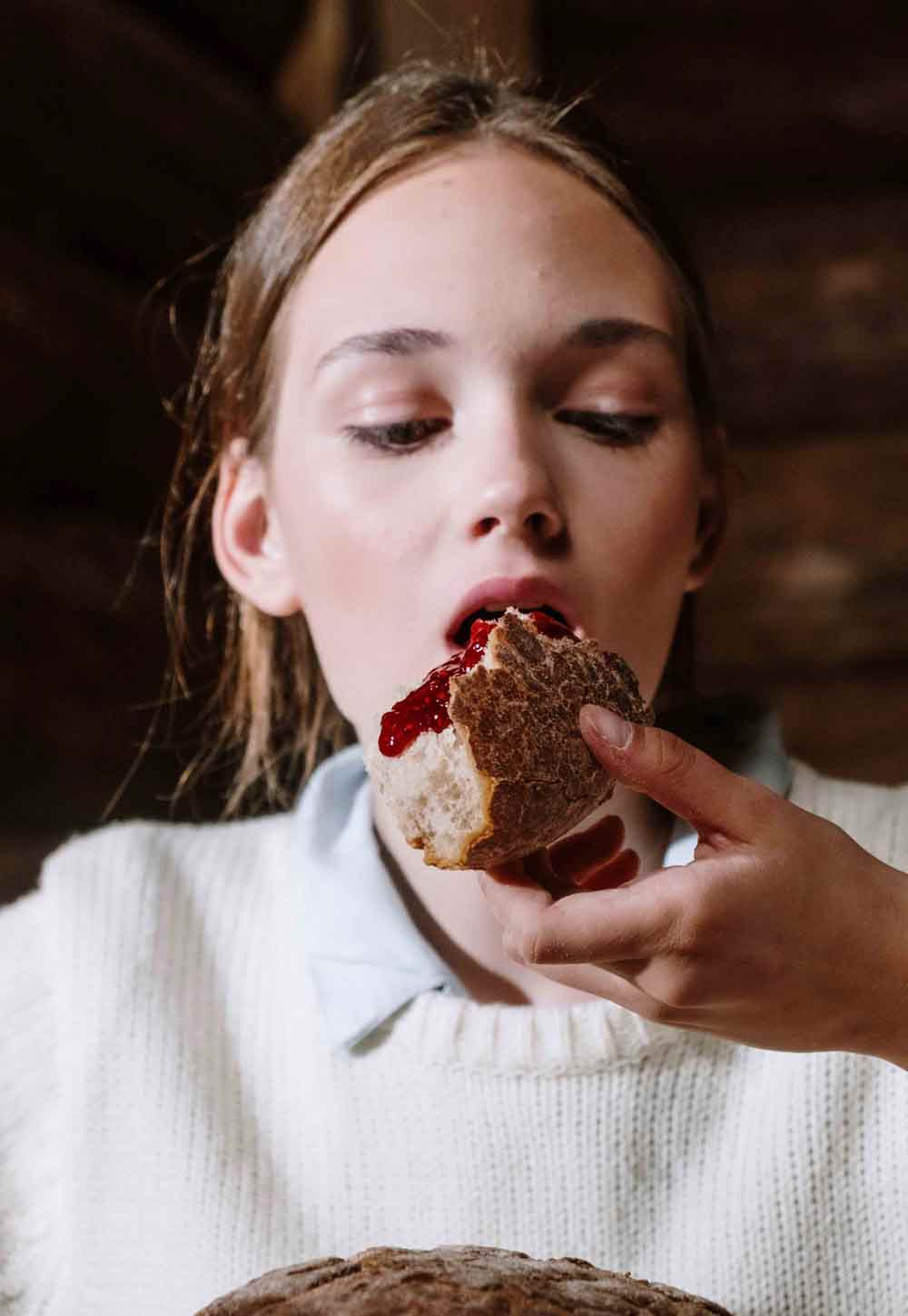 Jonge vrouw eet brood met jam.